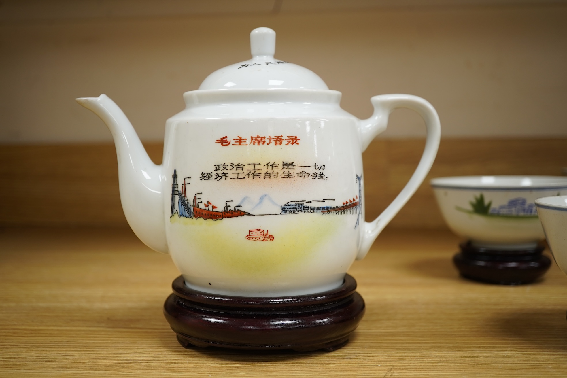 A Chinese Cultural Revolution porcelain teapot, six bowls, wood stands and an enamel tray-29.5cm diameter. (8)